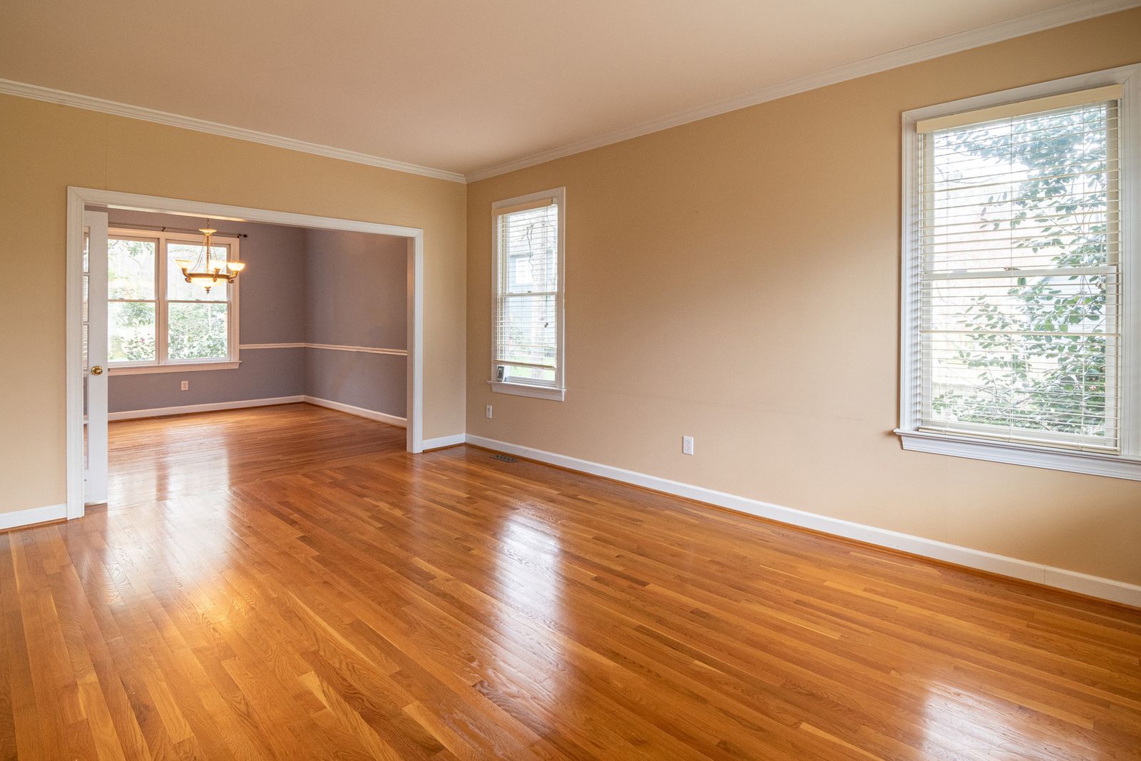 An empty room with wooden floors and a sunny window
